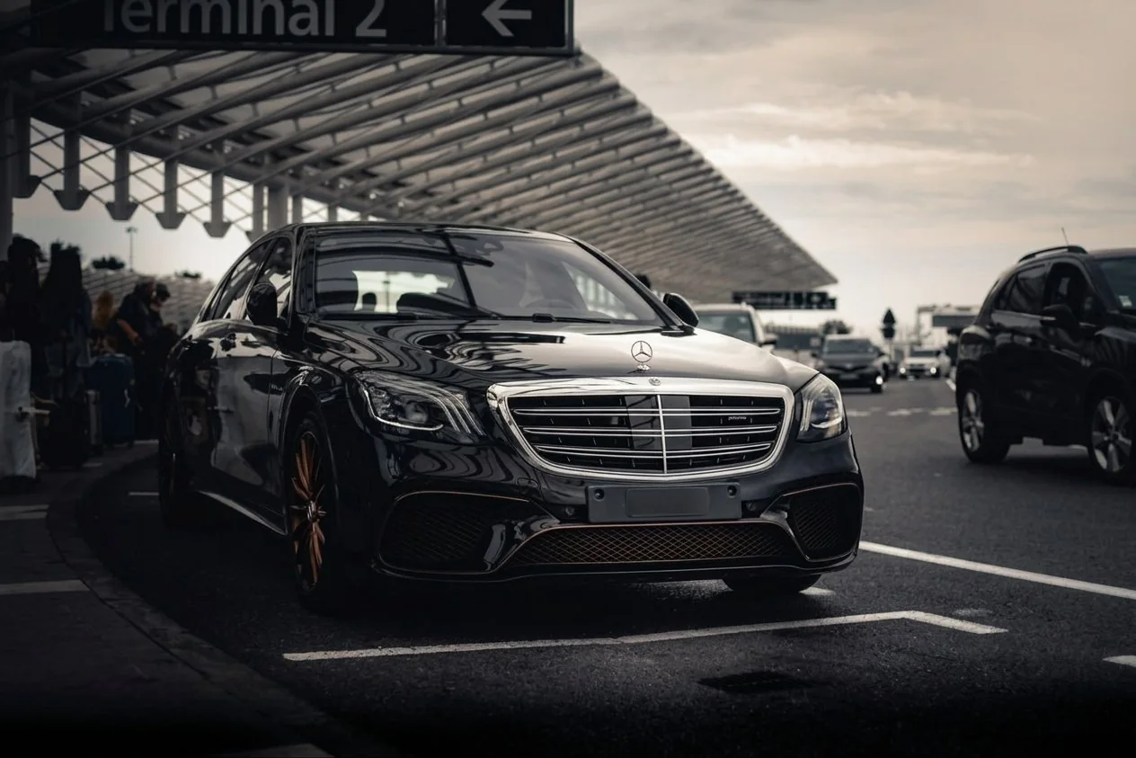 Black Mercedes saloon waiting under the airport terminal canopy for a private transfer